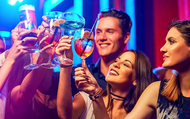 Friends raising glasses in a vibrant club setting.