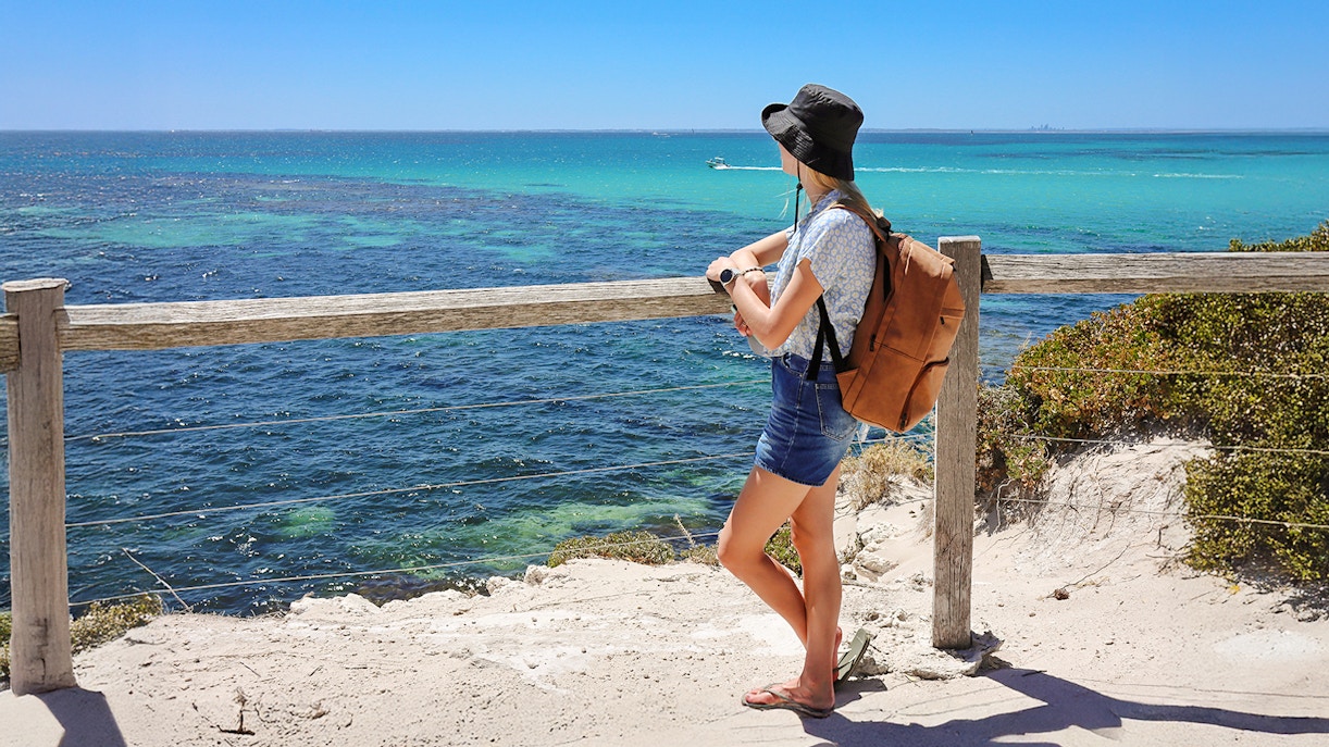 Woman enjoying ocean view from Rottnest Island lookout.