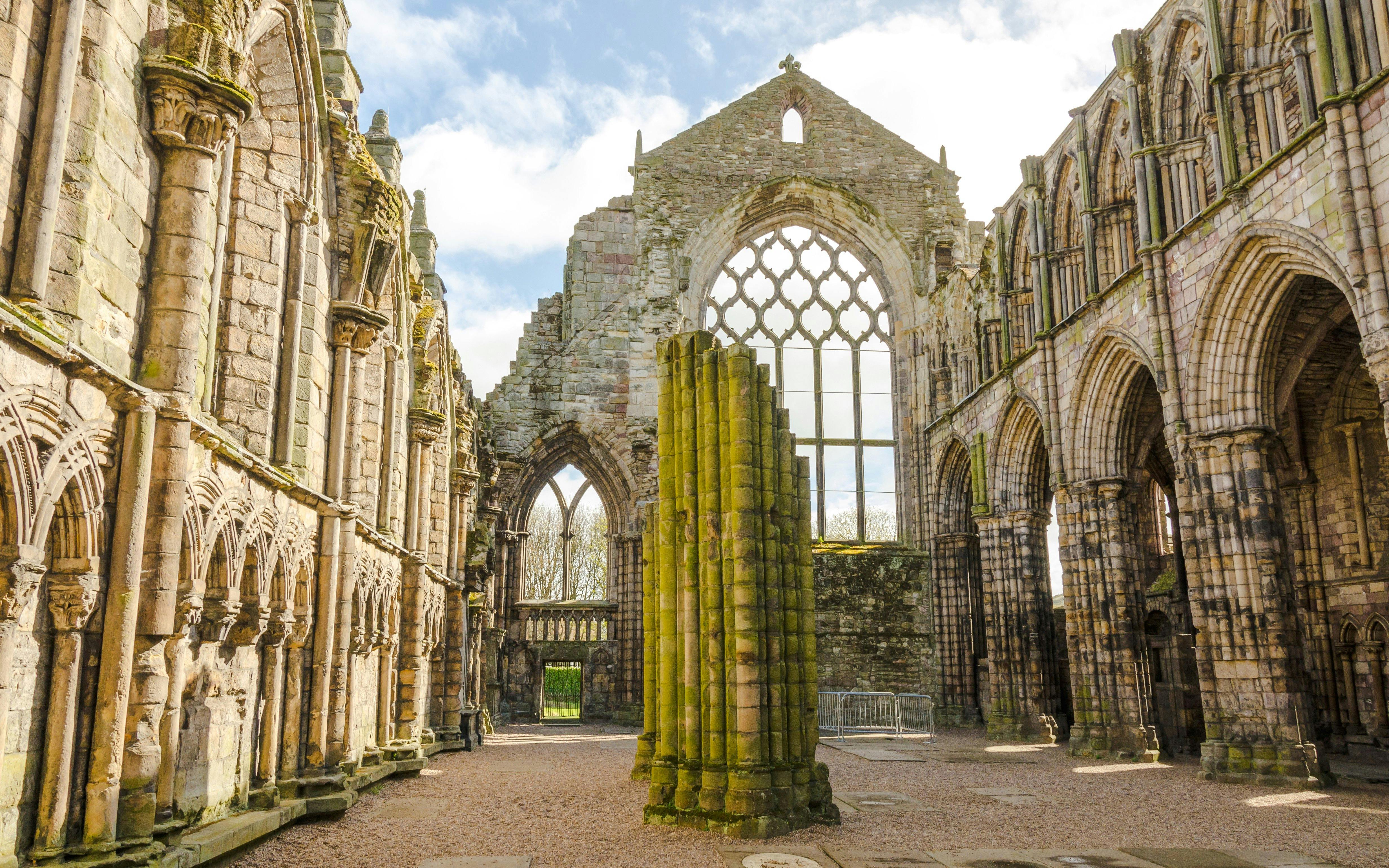 Ruins of Holyrood Abbey with stone arches and columns in Edinburgh, Scotland.