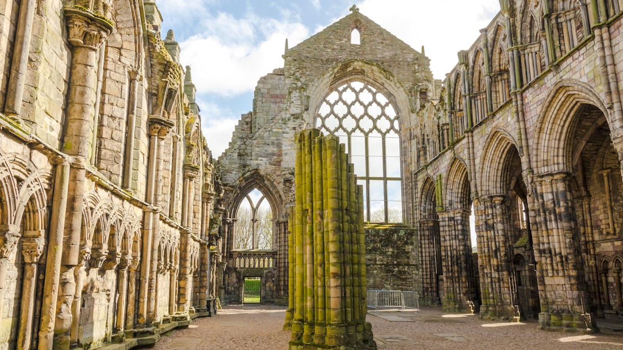 Ruins of Holyrood Abbey with stone arches and columns in Edinburgh, Scotland.