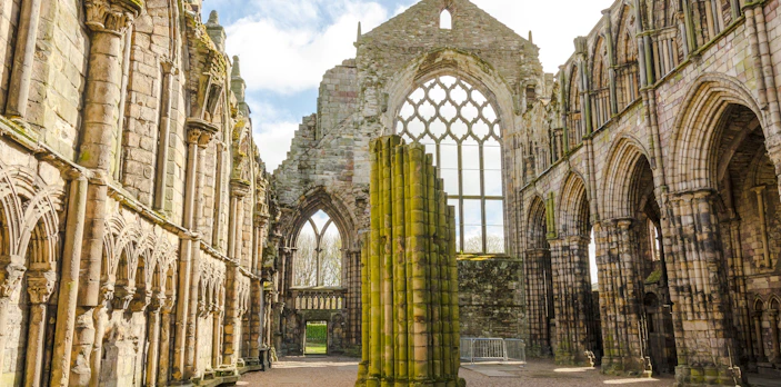 Ruins of Holyrood Abbey with stone arches and columns in Edinburgh, Scotland.