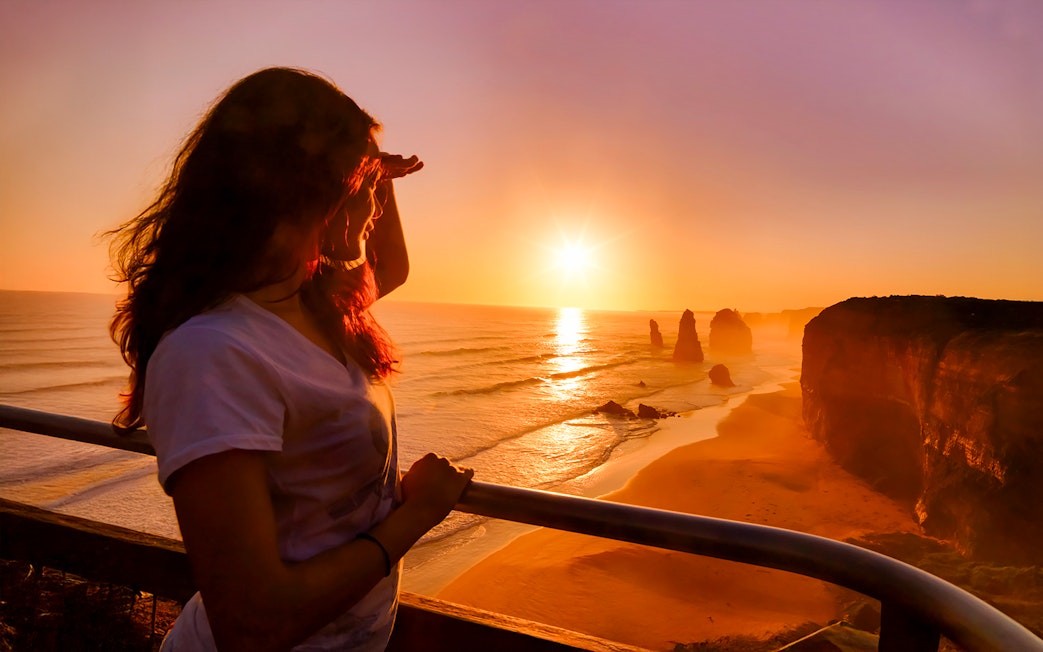 Woman viewing sunset at 12 Apostles on Great Ocean Road tour.