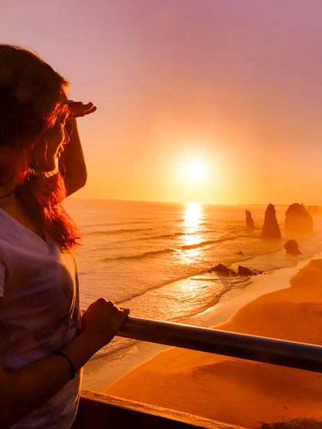 Woman viewing sunset at 12 Apostles on Great Ocean Road tour.