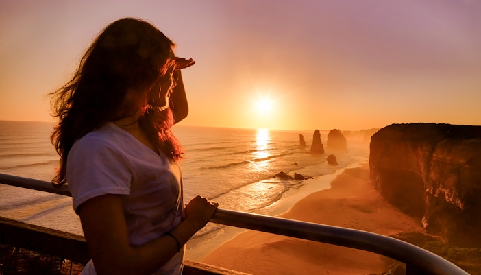 Woman admiring sunset at 12 Apostles on Great Ocean Road Sunset Tour, Melbourne.