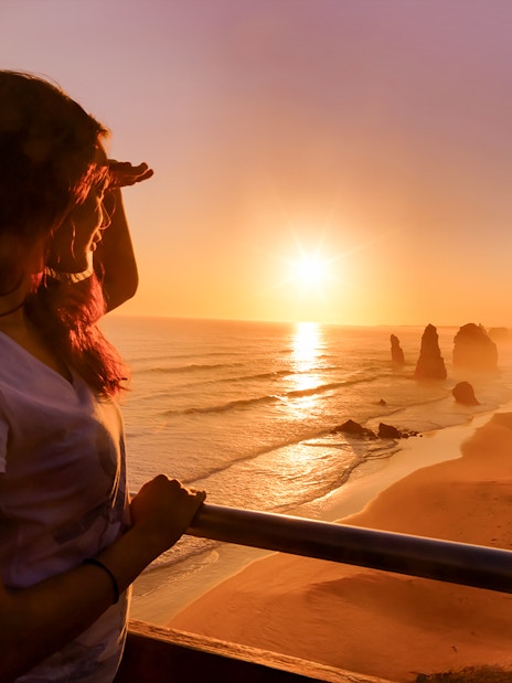 Woman viewing sunset at 12 Apostles on Great Ocean Road tour.