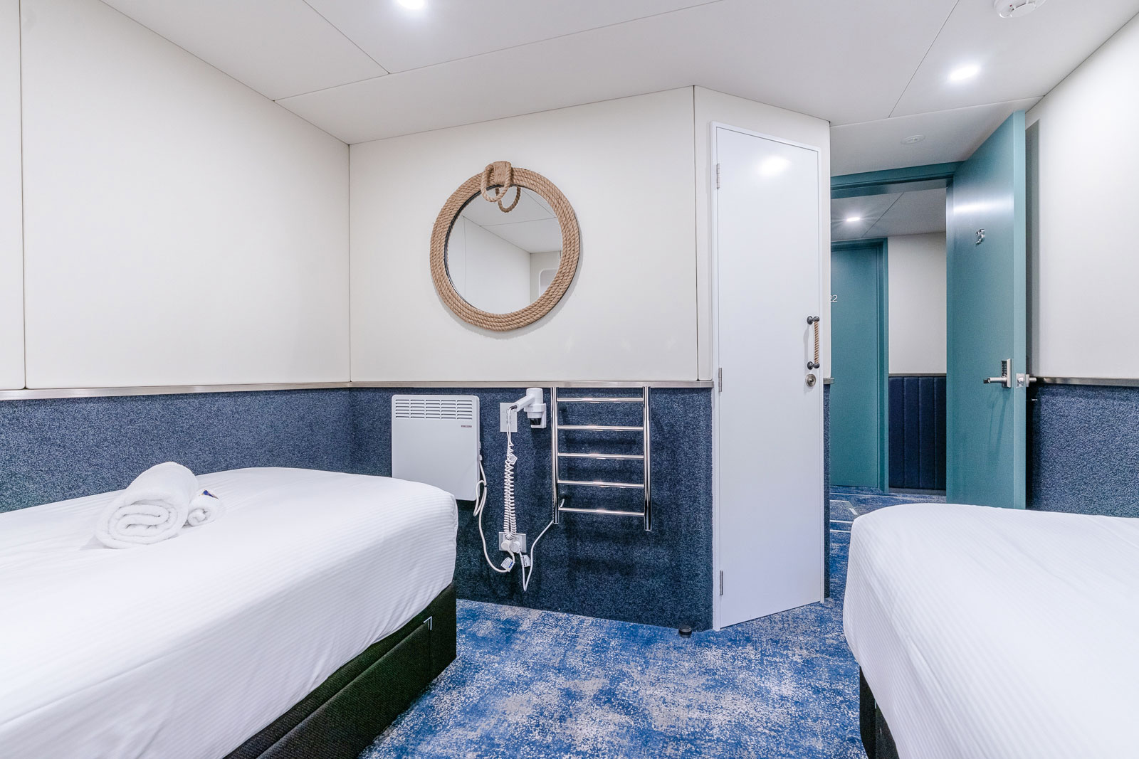Cruise ship cabin interior with twin beds and nautical decor.