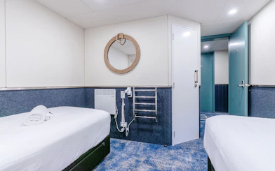 Cruise ship cabin interior with twin beds and nautical decor.