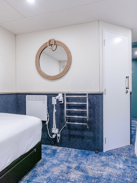 Cruise ship cabin interior with twin beds and nautical decor.