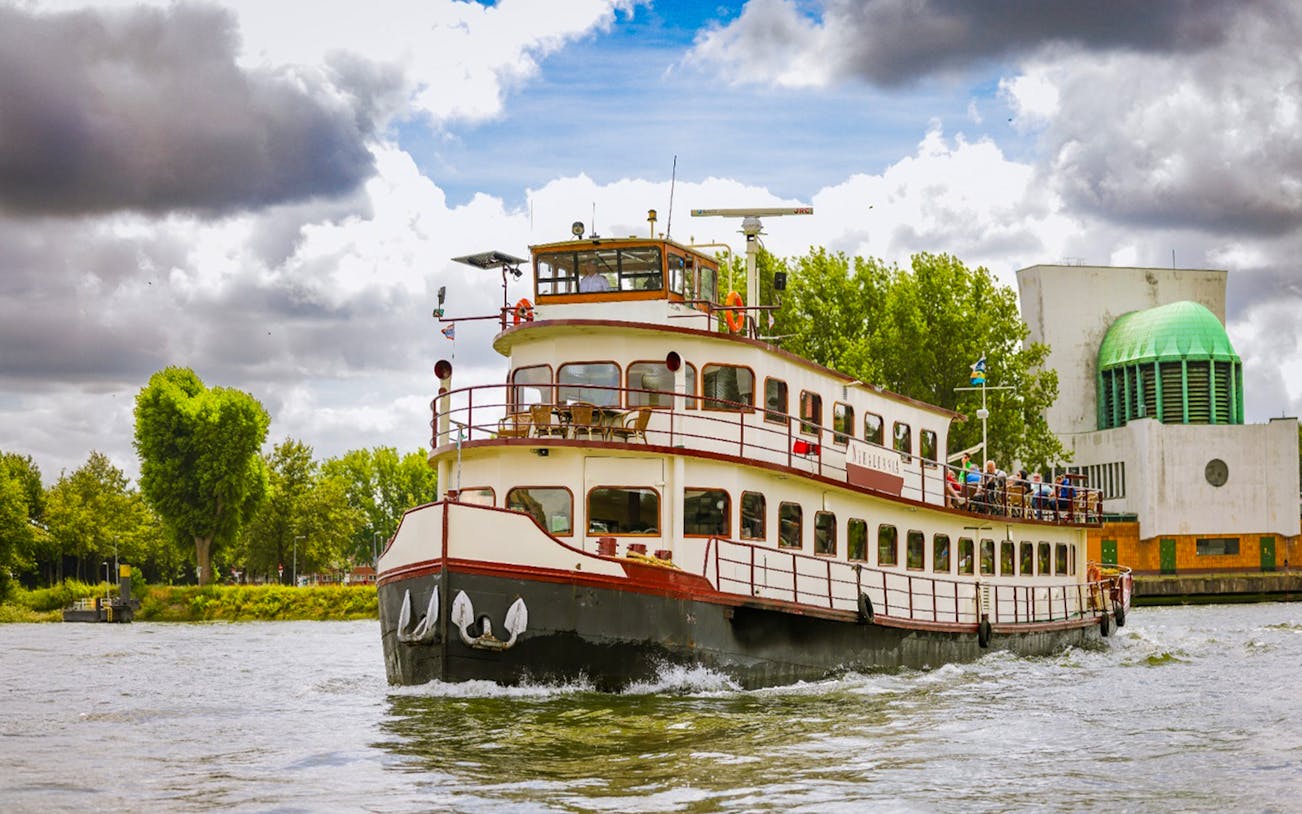 Historic ship cruising Rotterdam Harbour with passengers on deck.