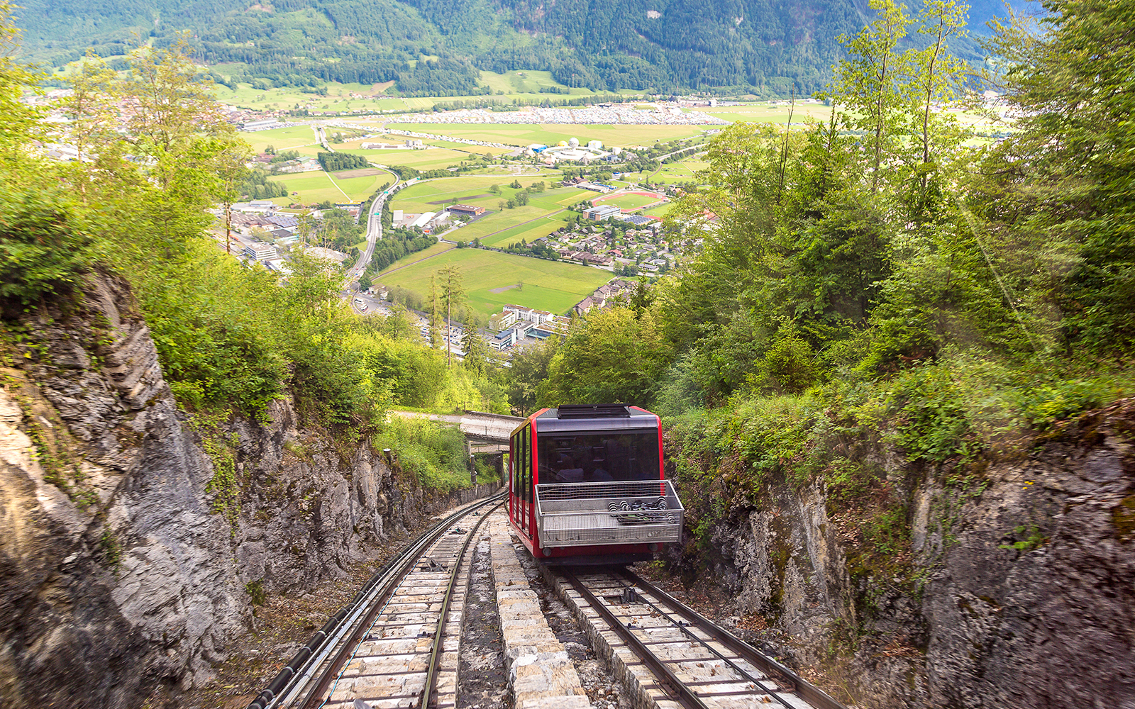 Train descending through lush mountains on the way to Interlaken from Zürich.
