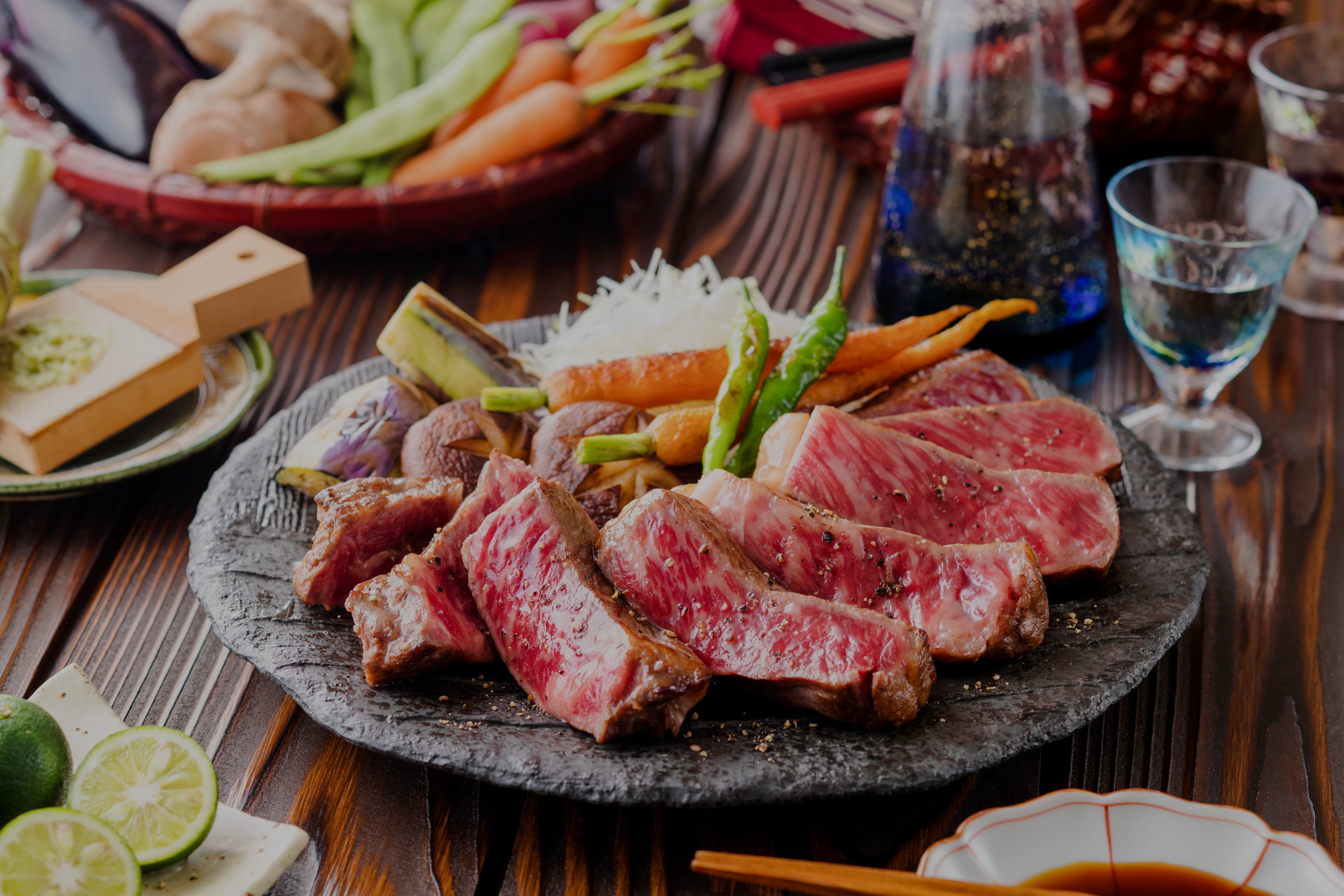 Wagyu steak served with grilled vegetables on a stone plate.
