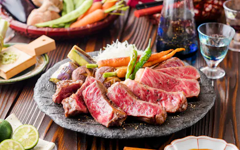 Wagyu steak served with grilled vegetables on a stone plate.