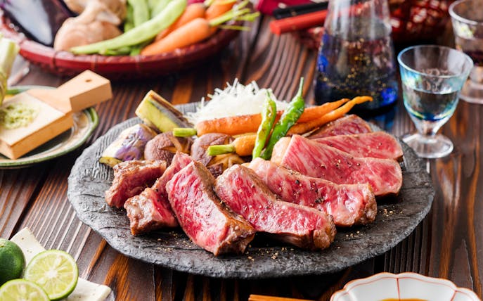 Wagyu steak served with grilled vegetables on a stone plate.