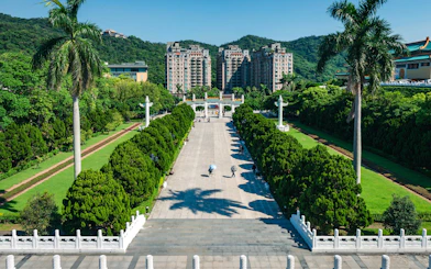 Walkway leading to Taiwan Palace Museum with lush greenery and distant buildings.