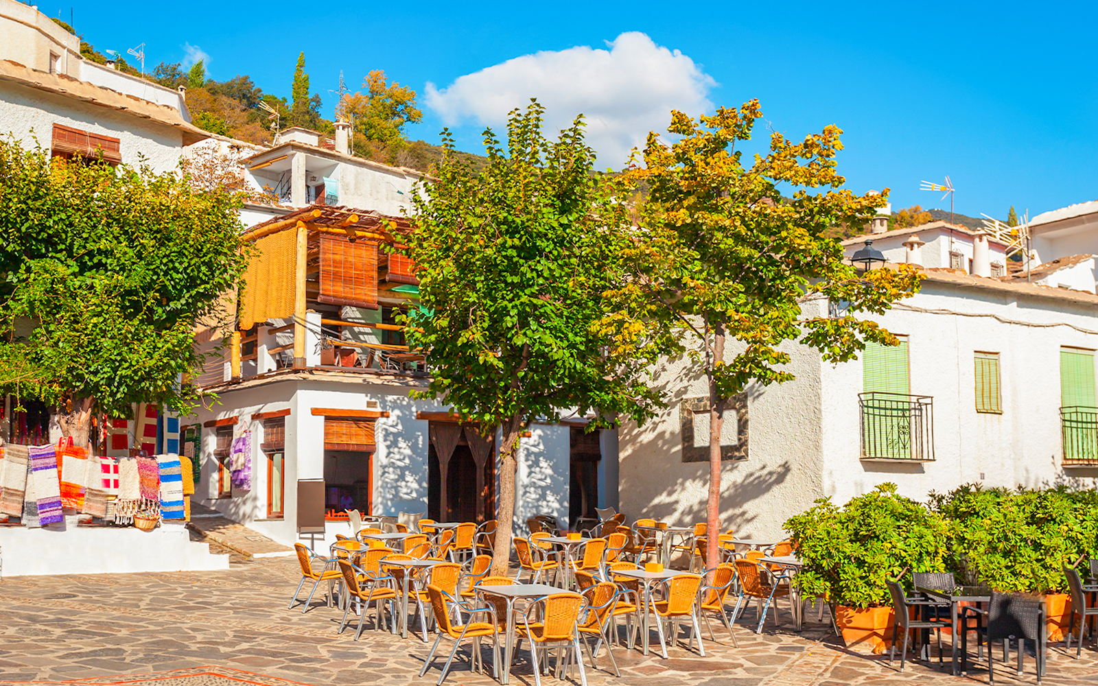 Outdoor café and colorful textiles in Pampaneira village, Alpujarras, Andalusia, Spain.
