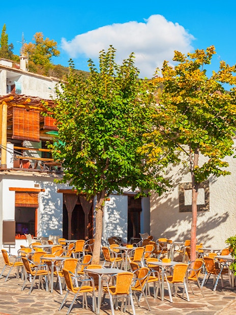 Outdoor café and colorful textiles in Pampaneira village, Alpujarras, Andalusia, Spain.