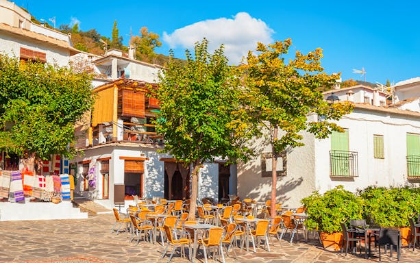 Outdoor café and colorful textiles in Pampaneira village, Alpujarras, Andalusia, Spain.