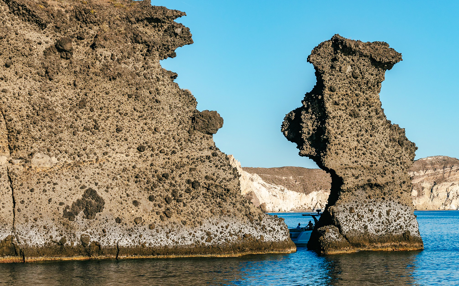 Rock formations with a boat near Indian Rock, Santorini.
