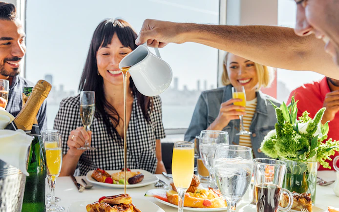 Guests enjoying brunch with mimosas on a New York Signature Dinner Cruise.