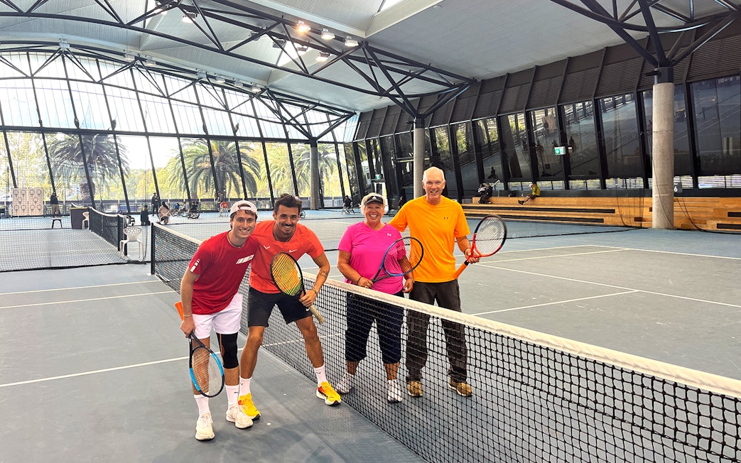 Tennis players posing on an indoor court at Melbourne Park during a sports walking tour.