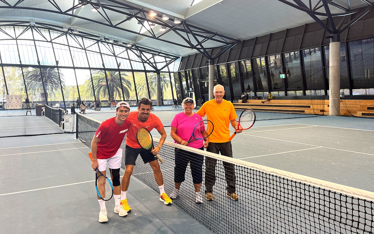 Tennis players posing on an indoor court at Melbourne Park during a sports walking tour.