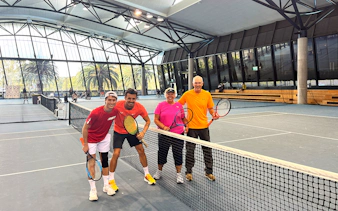 Tennis players posing on an indoor court at Melbourne Park during a sports walking tour.