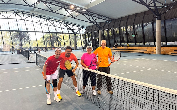 Tennis players posing on an indoor court at Melbourne Park during a sports walking tour.
