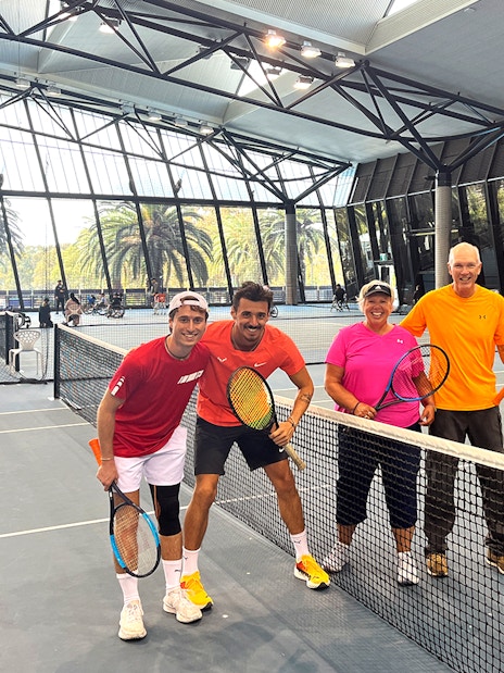 Tennis players posing on an indoor court at Melbourne Park during a sports walking tour.