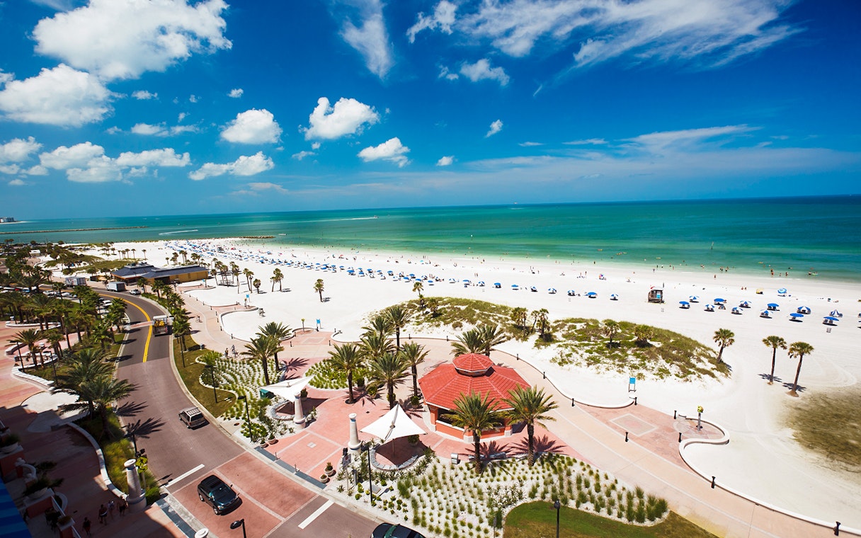 Clearwater Beach with umbrellas and palm trees along the shoreline, ideal for Sea Screamer Boat Ride.