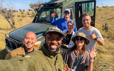 Group enjoying a safari in Masai Mara with a jeep in the background.