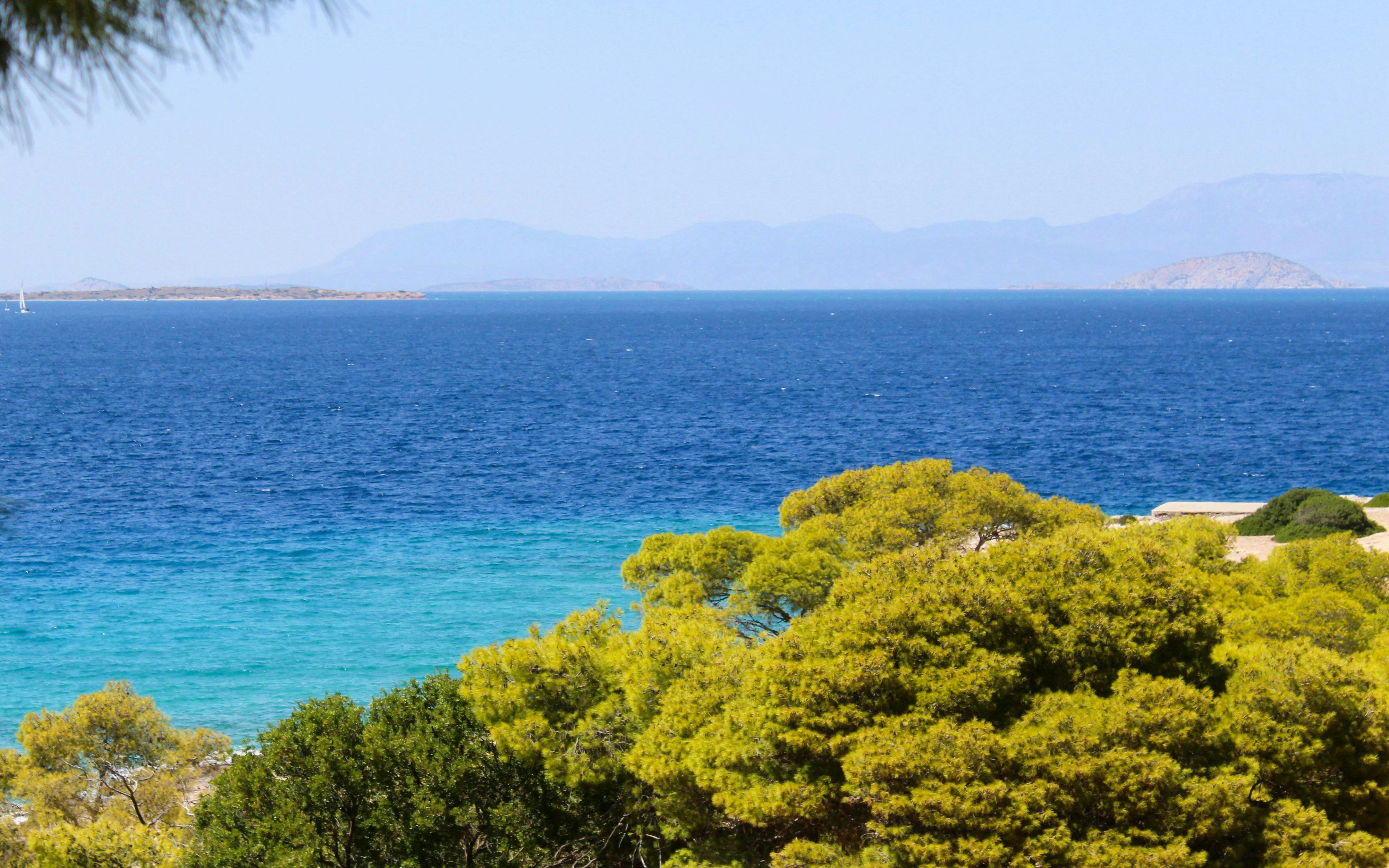 View of Moni Island with turquoise waters and lush greenery, Aegina, Saronic Gulf, Greece.
