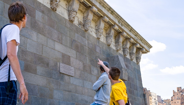 Tour participants observing architectural details on Notre Dame islands, Paris.