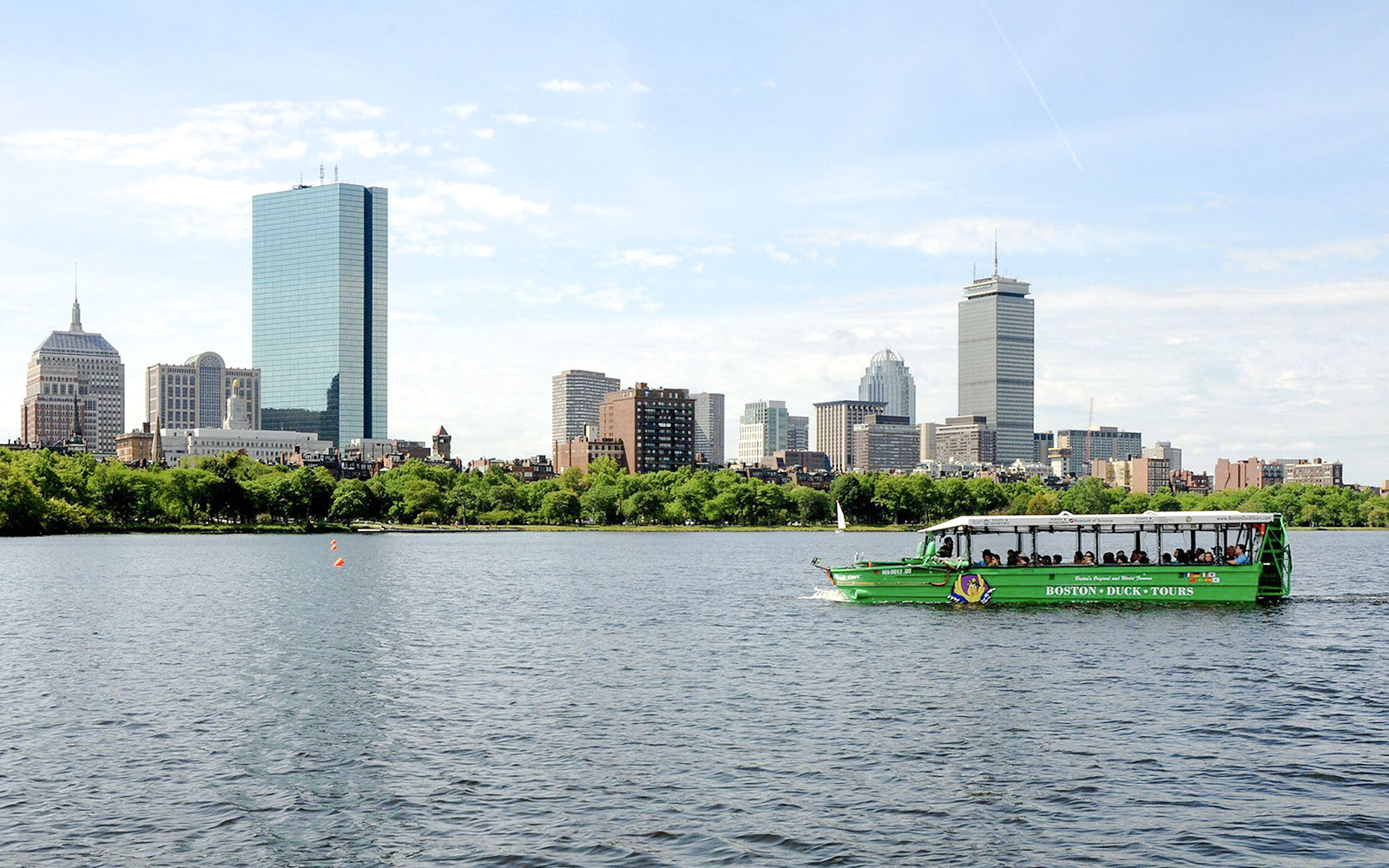 Boston Duck Tours vehicle cruising on Charles River with Boston skyline in background.
