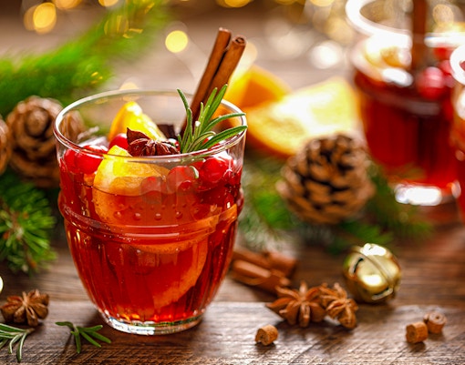 Mulled wine with cinnamon sticks and orange slices on a festive table.