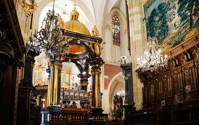 Interior of Wawel Cathedral with ornate chandeliers and detailed wood carvings.