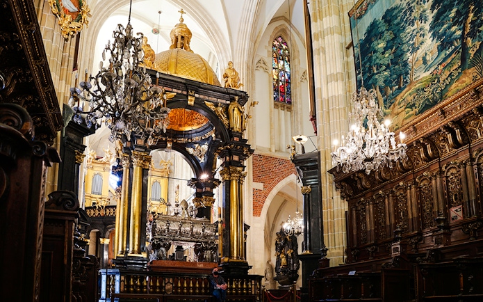 Interior of Wawel Cathedral with ornate chandeliers and detailed wood carvings.