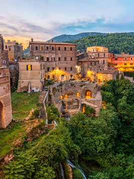 Villa Gregoriana in Tivoli, Italy, with historic buildings and lush greenery at sunset.