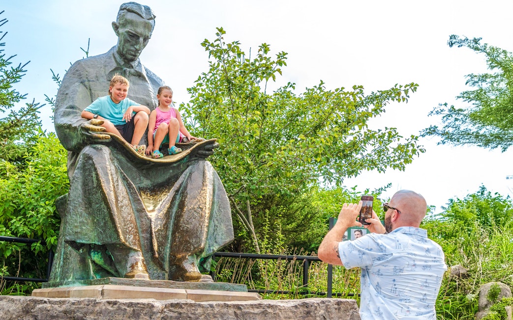 Children sitting on Nikola Tesla Monument at Niagara Falls State Park, Goat Island, New York.