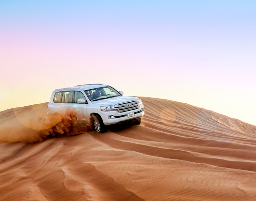 Dubai evening desert safari with camel ride and sand dunes at sunset.