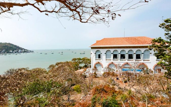 Colonial building overlooking Vũng Tàu Beach with boats in the distance, part of the Ho Chi Minh City tour.