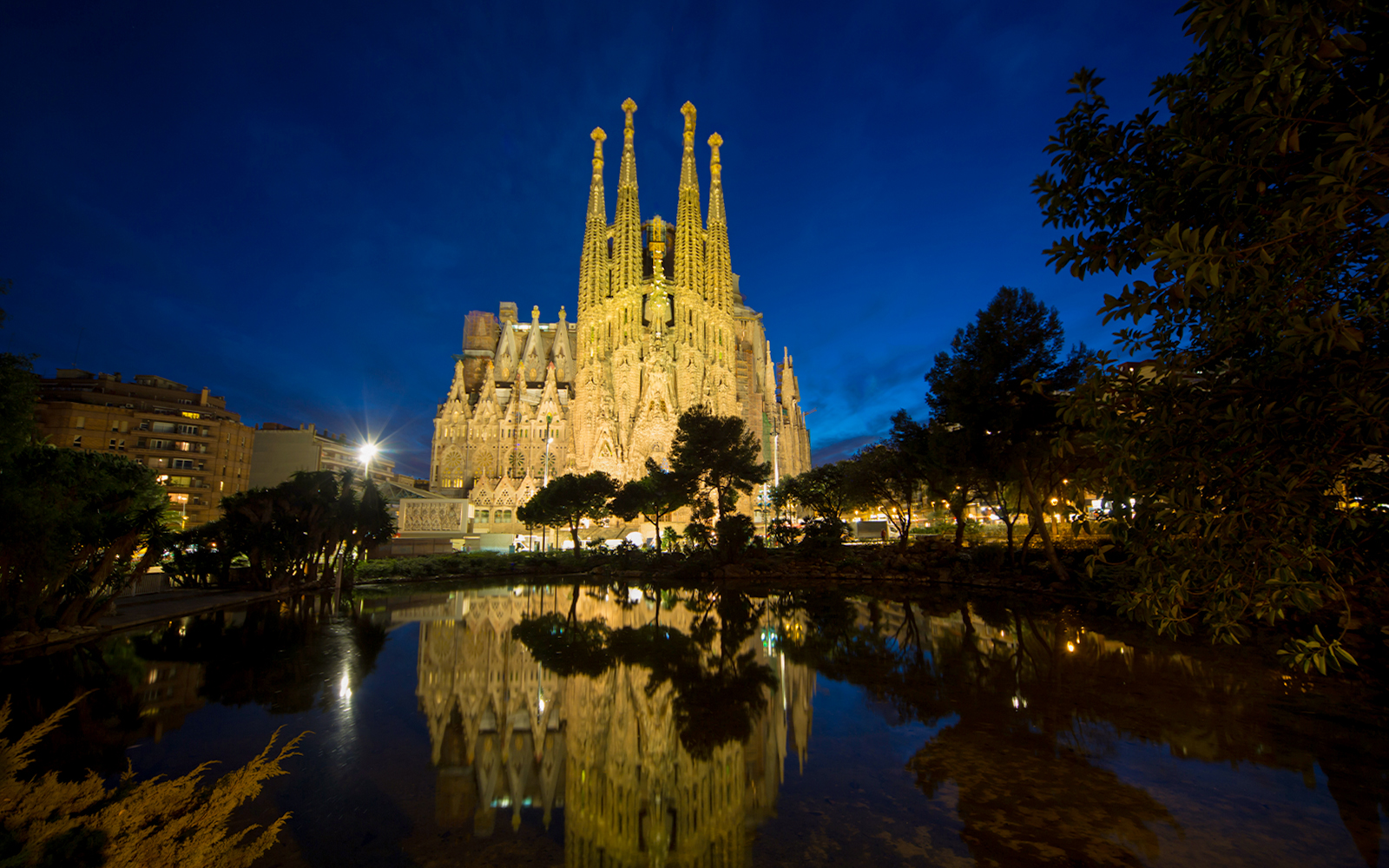 Sagrada Familia illuminated at night with reflection in water, Barcelona.