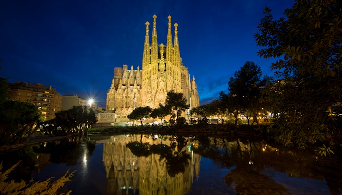Sagrada Familia illuminated at night with reflection in water, Barcelona.