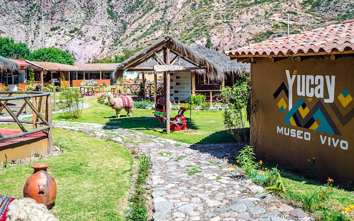 Yucay Museo de Cultura Viva entrance with traditional textiles and alpaca in Sacred Valley, Peru.