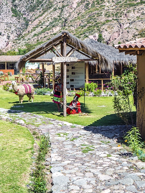 Yucay Museo de Cultura Viva entrance with traditional textiles and alpaca in Sacred Valley, Peru.