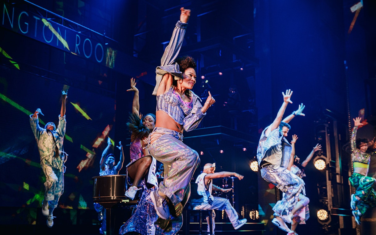 Performers dancing energetically on stage in Hell's Kitchen show.