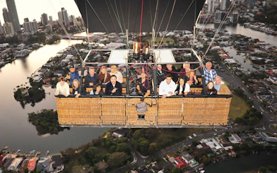 Group enjoying hot air balloon flight over cityscape with optional transfers.