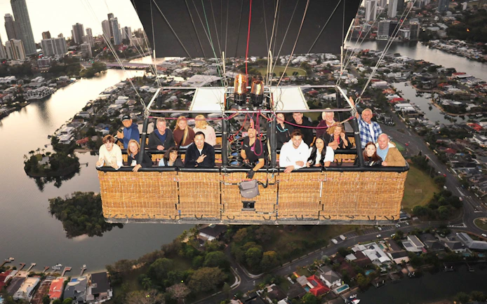 Group enjoying hot air balloon flight over cityscape with optional transfers.