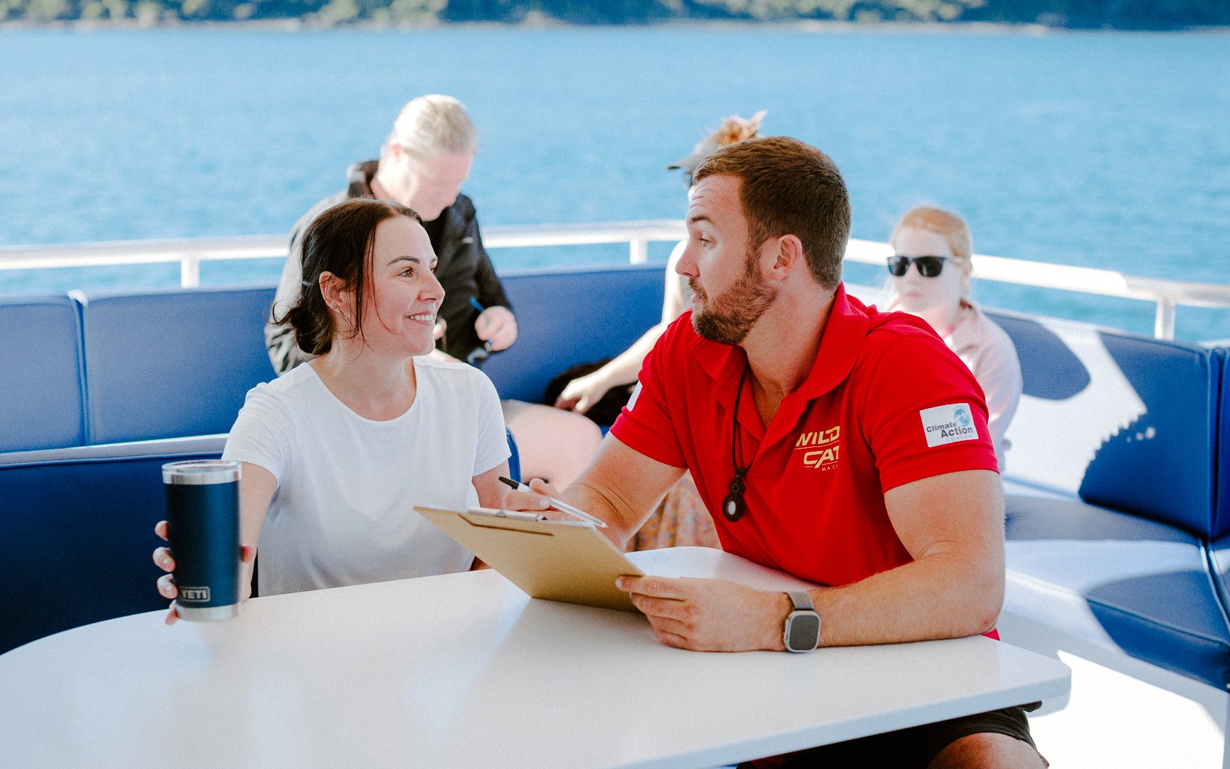 Tour guide discussing itinerary with a guest on a boat during Airlie Beach cruise.