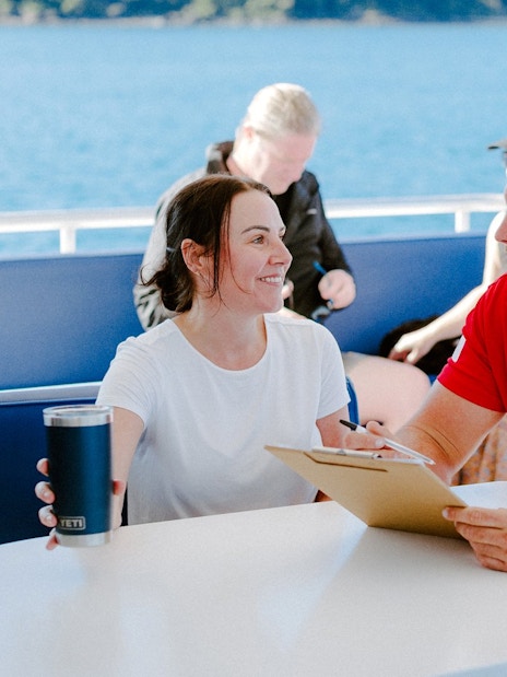 Tour guide discussing itinerary with a guest on a boat during Airlie Beach cruise.