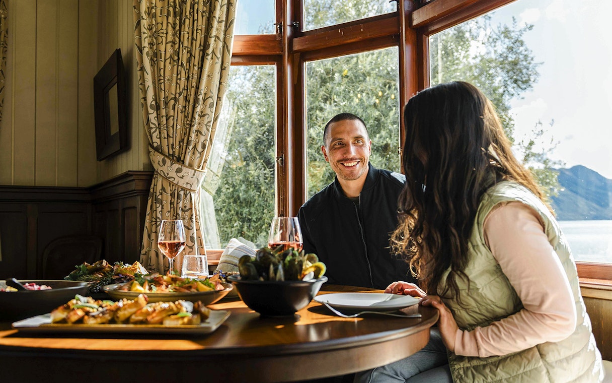Couple enjoying a meal at Walter Peak Gourmet BBQ Experience with lake view.